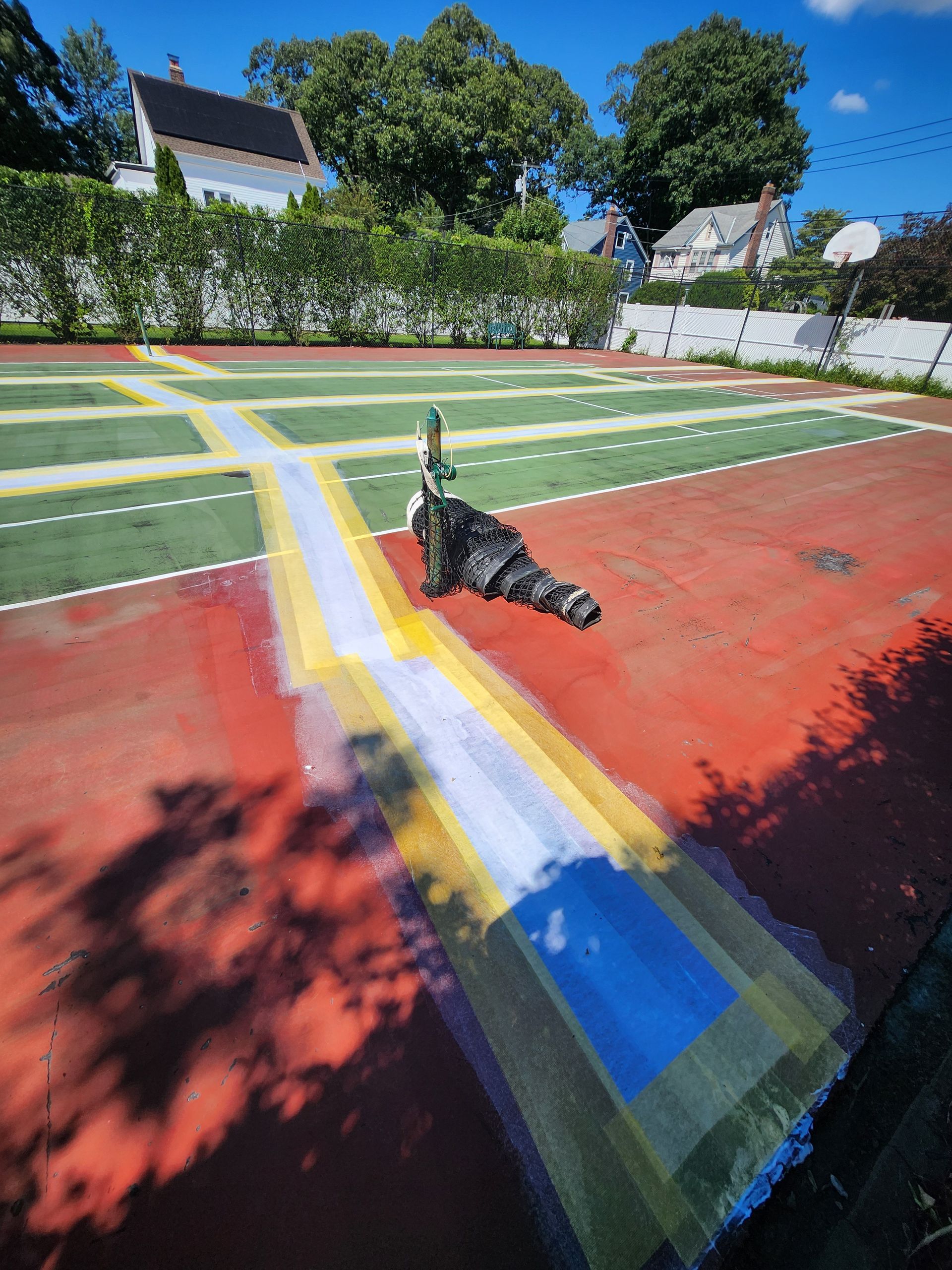 A basketball court is being painted with a blue and yellow line