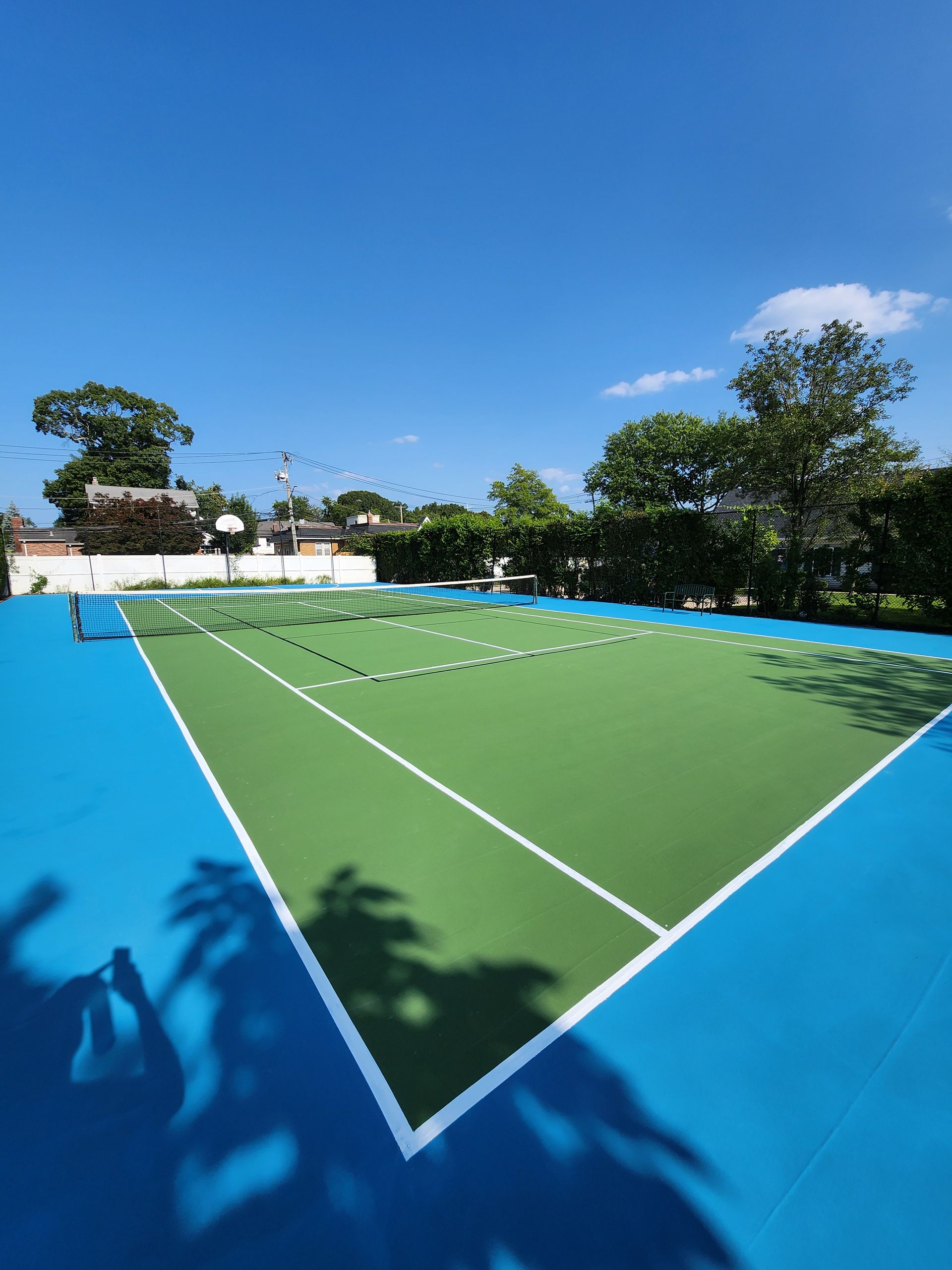 A blue and green tennis court with trees in the background