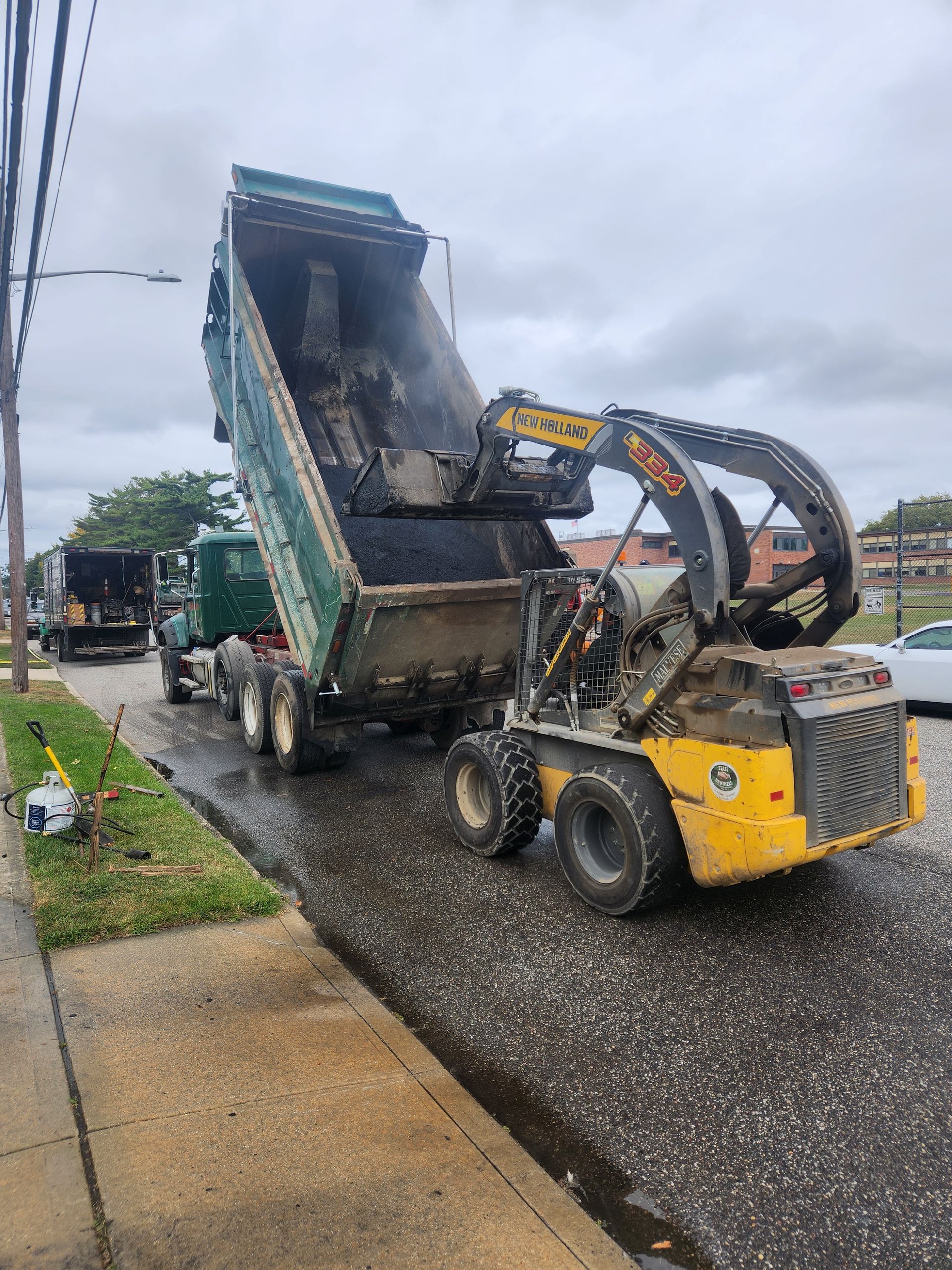A dump truck is being loaded with gravel by a small yellow truck.
