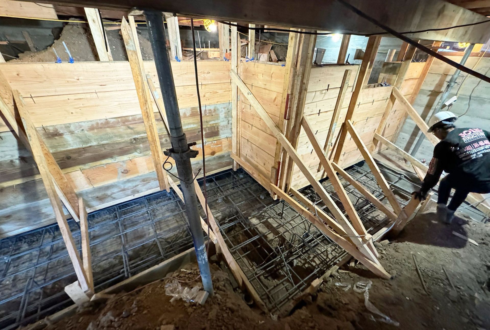 Wooden frame of a small building under construction, on a concrete base, against a blue sky.
