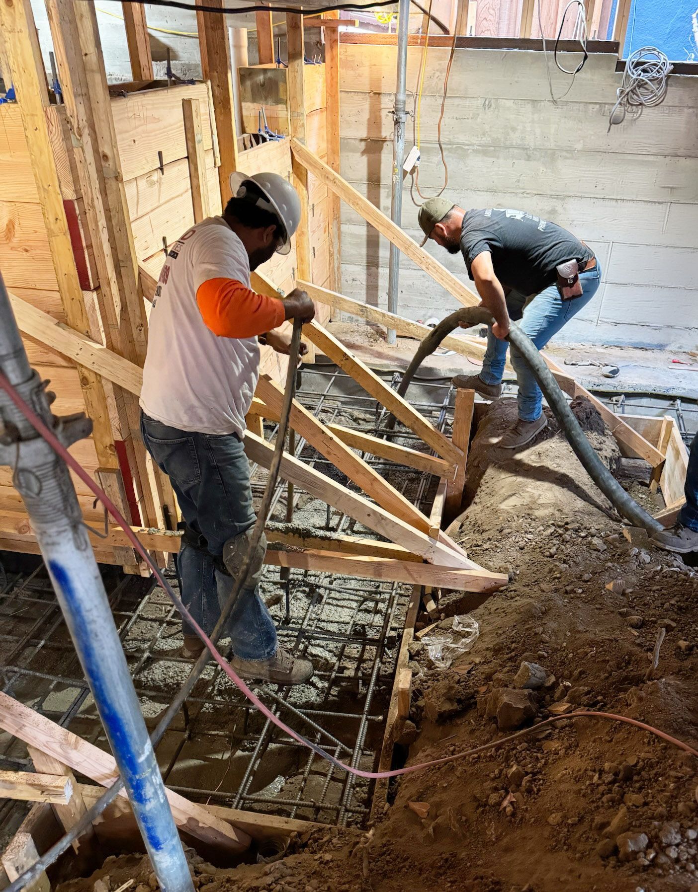 Construction workers reviewing blueprints at a building site, wearing hard hats and safety vests.