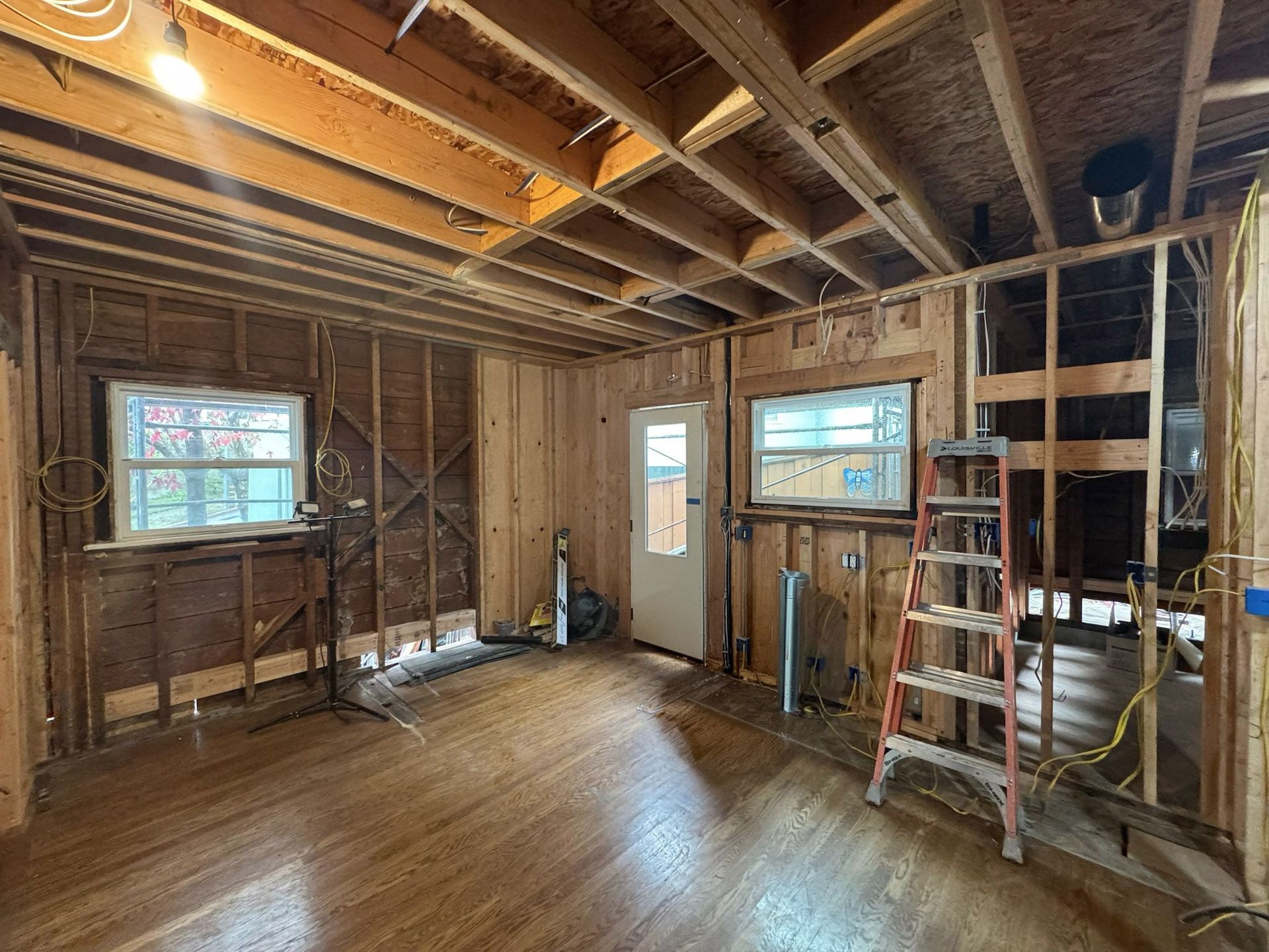 Construction workers in hard hats and vests review blueprints at a building site with heavy machinery.