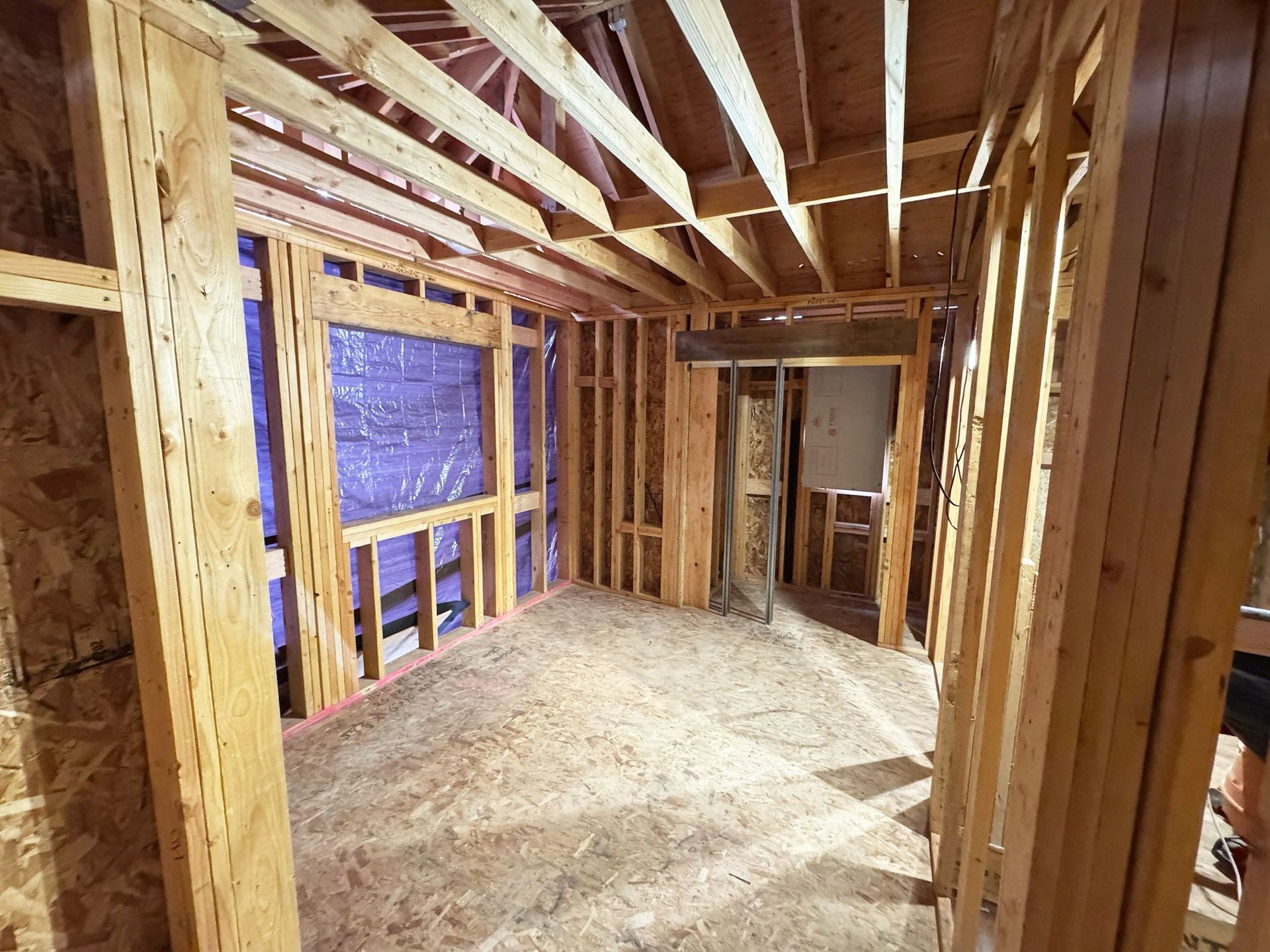 Two people in hard hats shaking hands in front of a building under construction.