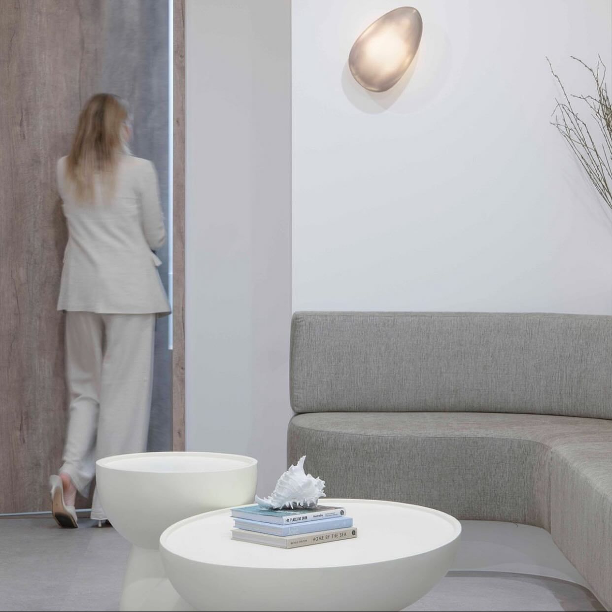 Woman in a White Suit Entering a Room With a Couch, Coffee Table, and Wall Sconce — McCormick Upholstery In Coolum Beach, QLD