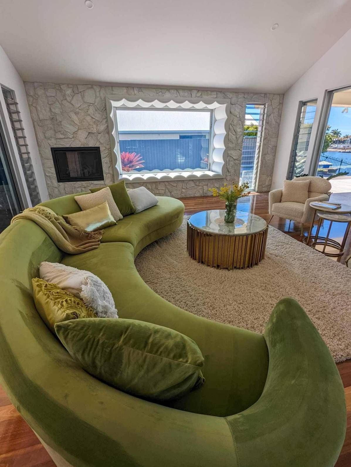 A Curved Green Couch in a Living Room With a Stone Fireplace — McCormick Upholstery In Coolum Beach, QLD