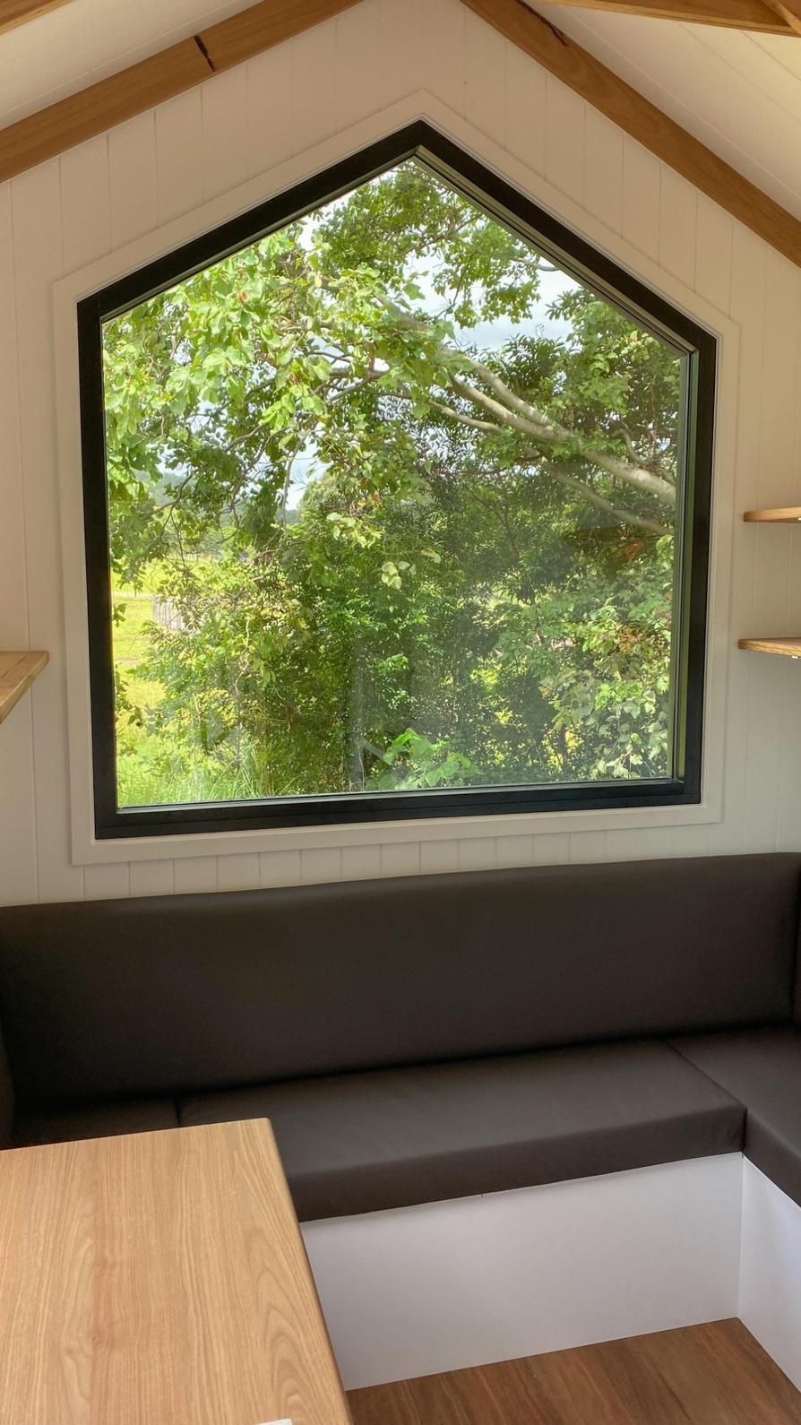 Interior View of a Tiny House With a Large, Angled Window Overlooking Green Trees — McCormick Upholstery In Coolum Beach, QLD