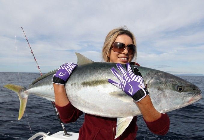 A woman is holding a large fish in her hands.