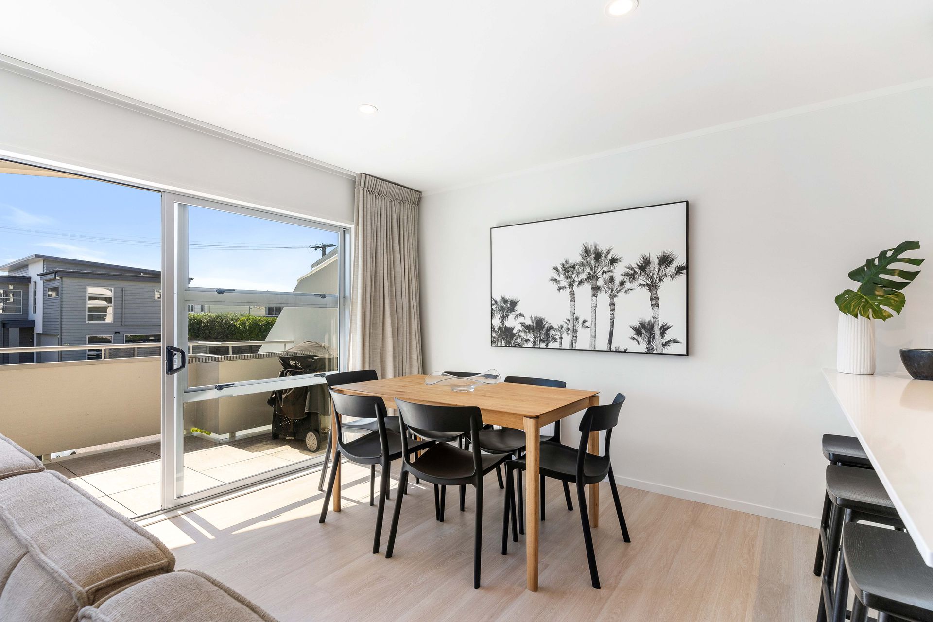 Dining area with table, chairs, artwork, and sliding door to balcony.