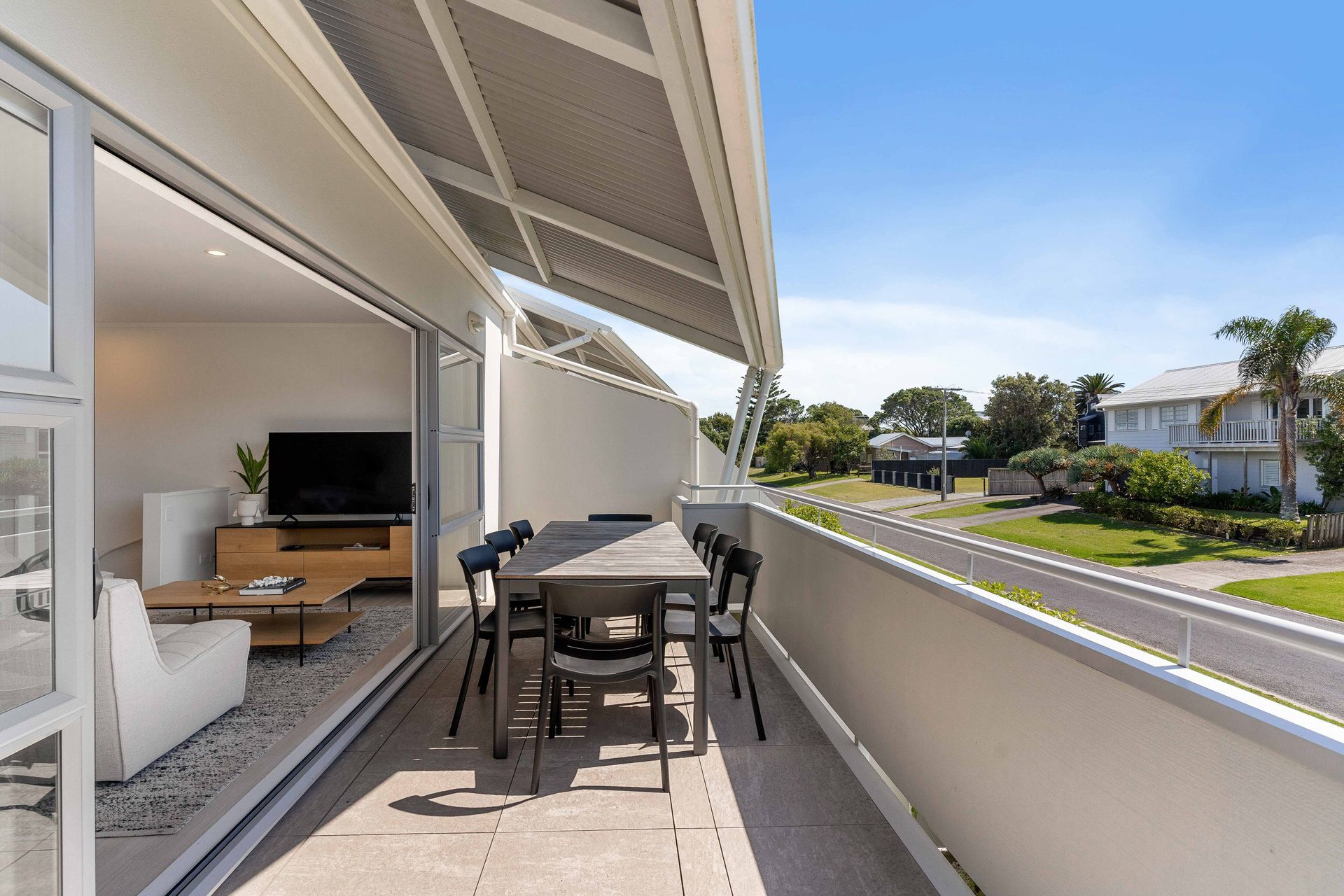 Balcony with outdoor dining set and partial view of interior and street.