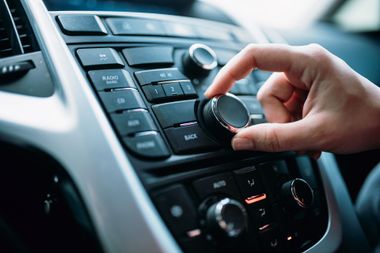 Una persona sta regolando la radio in un'auto.