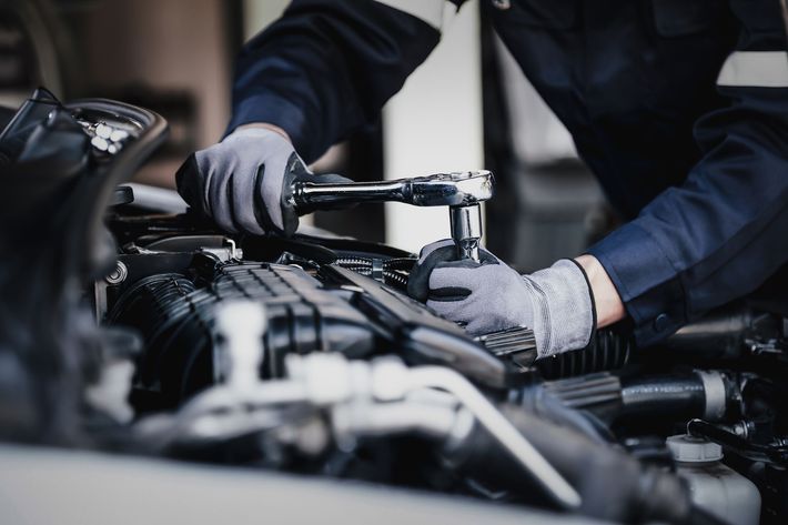 Un uomo sta lavorando al motore di un'auto con una chiave inglese.