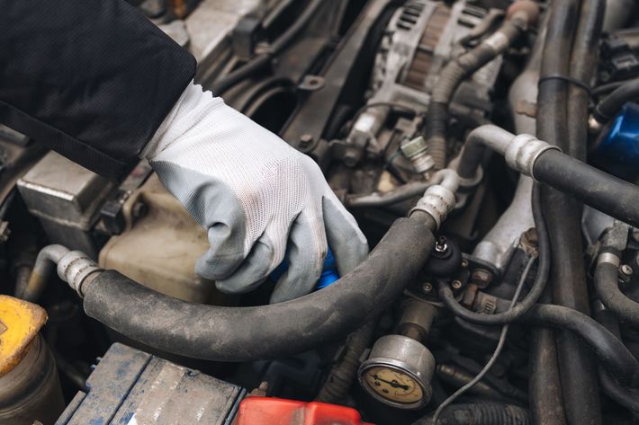 Una persona sta lavorando al motore di un'auto.