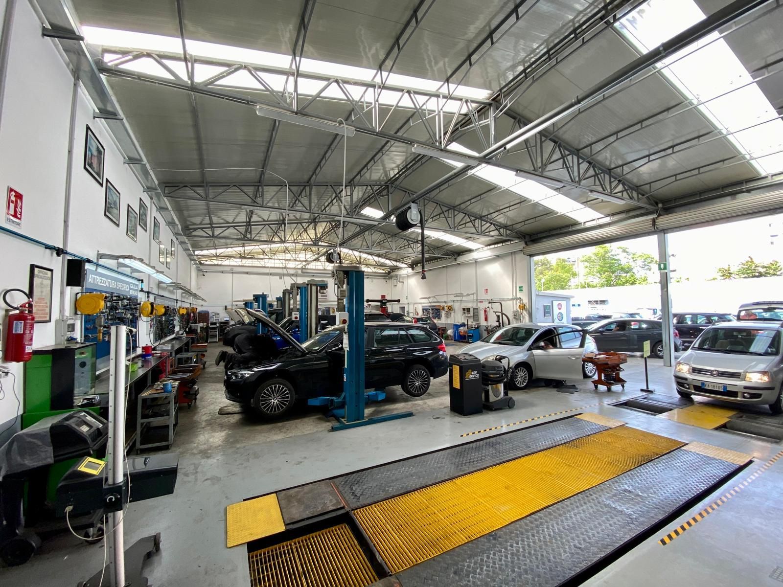 Un grande garage pieno di auto in lavorazione.