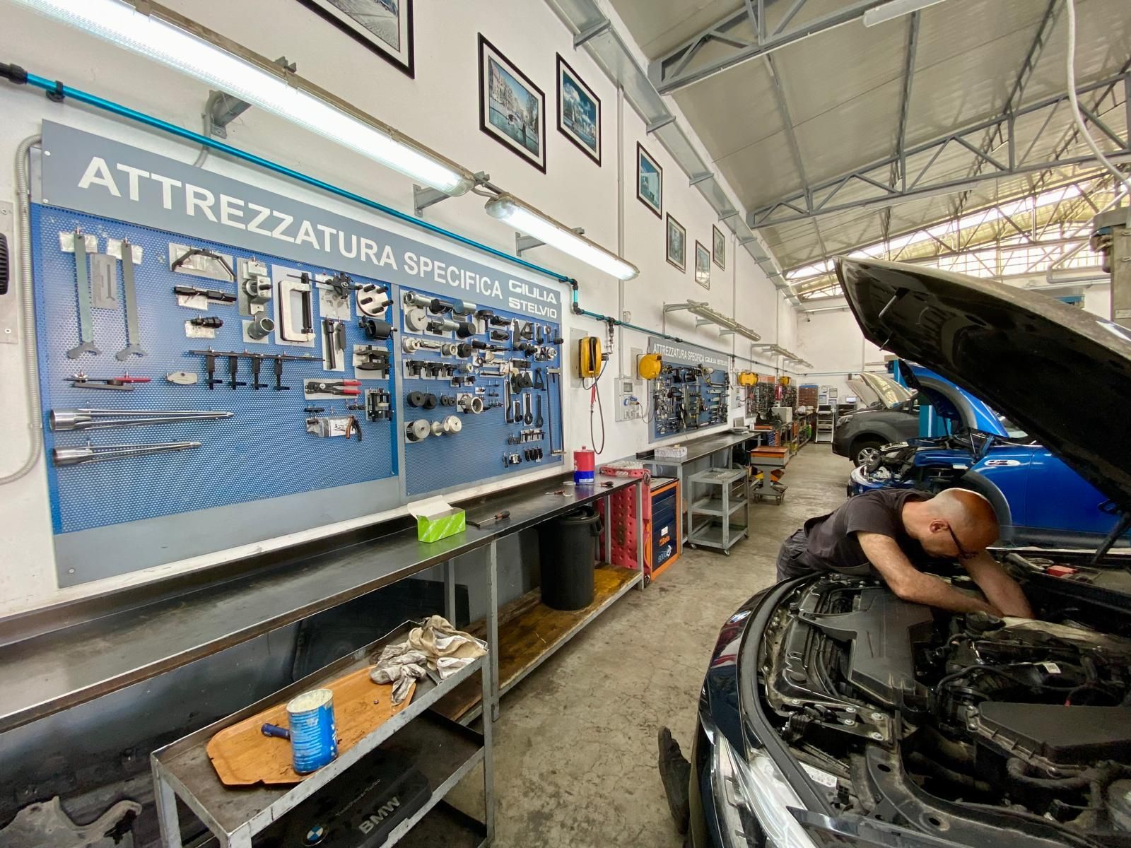 Un uomo sta lavorando al motore di un'auto in un garage.