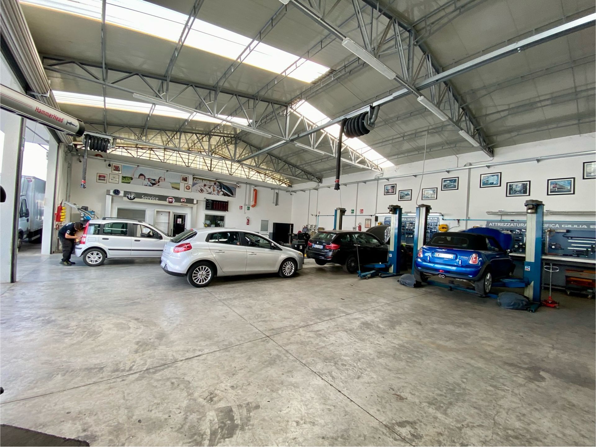 Un garage con auto parcheggiate al suo interno e un'auto blu su un ascensore.