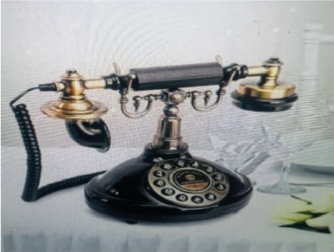 Black and gold antique telephone on a white table.