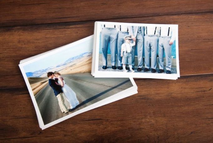 Stack of printed wedding photos on a wood table