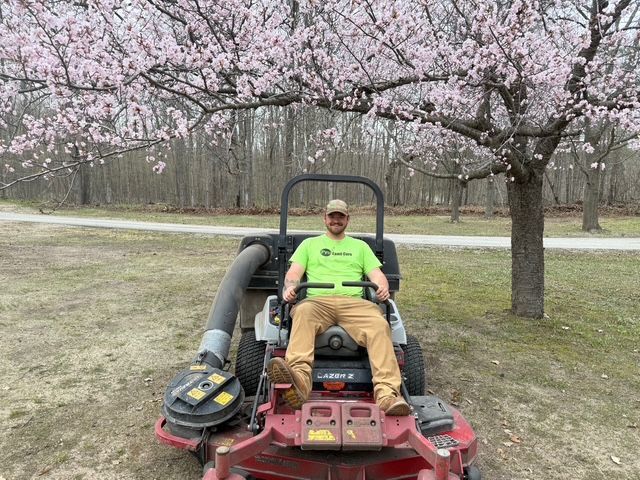 A man is riding a lawn mower on a lush green lawn.