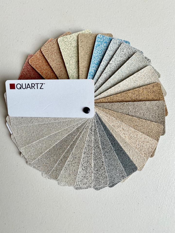 A color sample fan deck for quartz surfacing materials, featuring a variety of textured, neutral, and colored swatches.