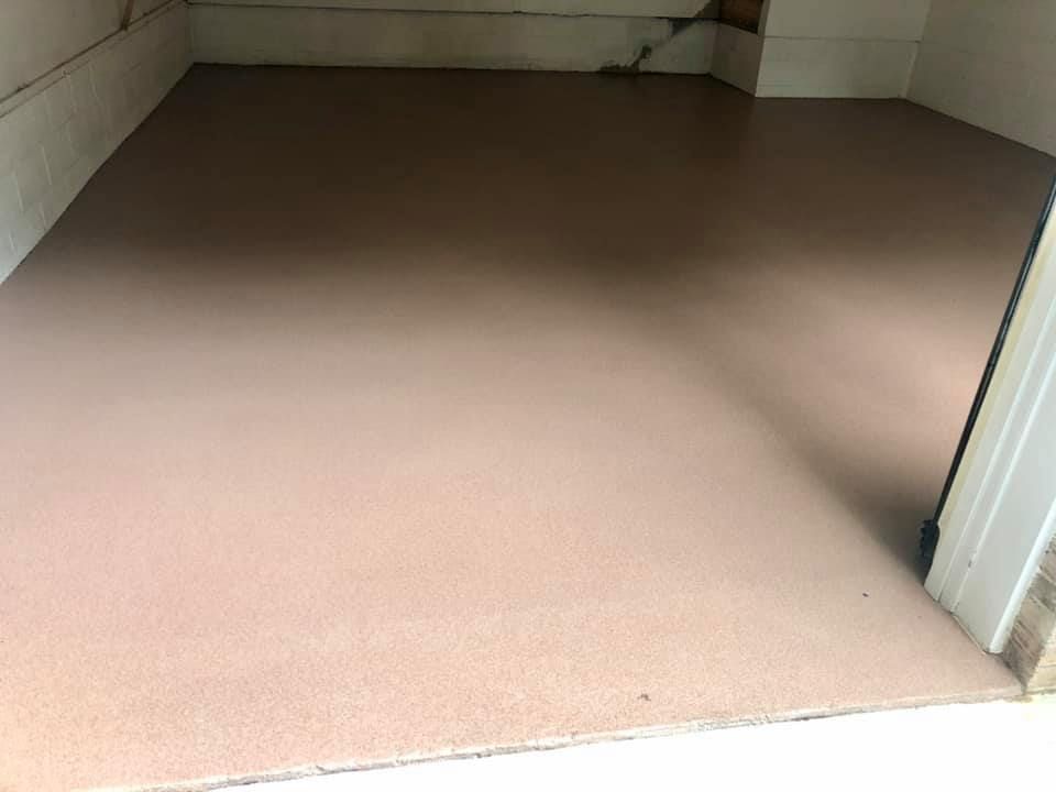 A freshly applied, smooth, beige epoxy floor coating in a garage interior.