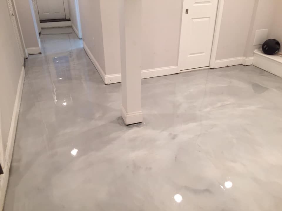 A modern interior hallway and room featuring a high-gloss, light gray metallic epoxy floor with a marbled finish.