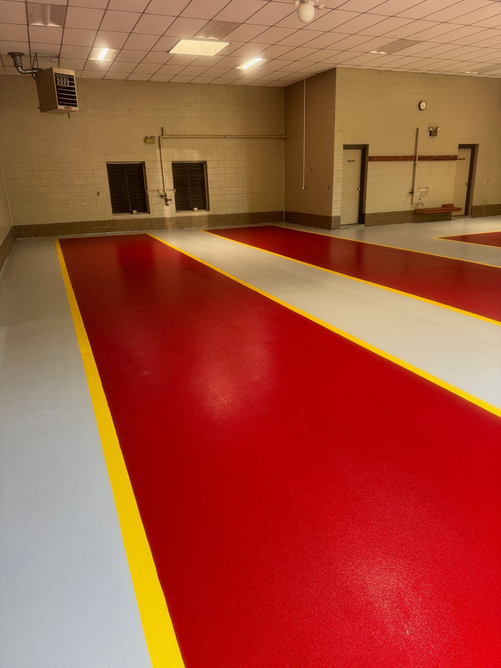 An indoor space with glossy red and light gray flooring separated by bright yellow painted safety lines.