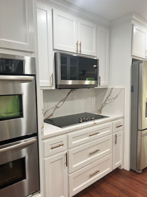 White kitchen with stainless steel appliances and gold hardware.