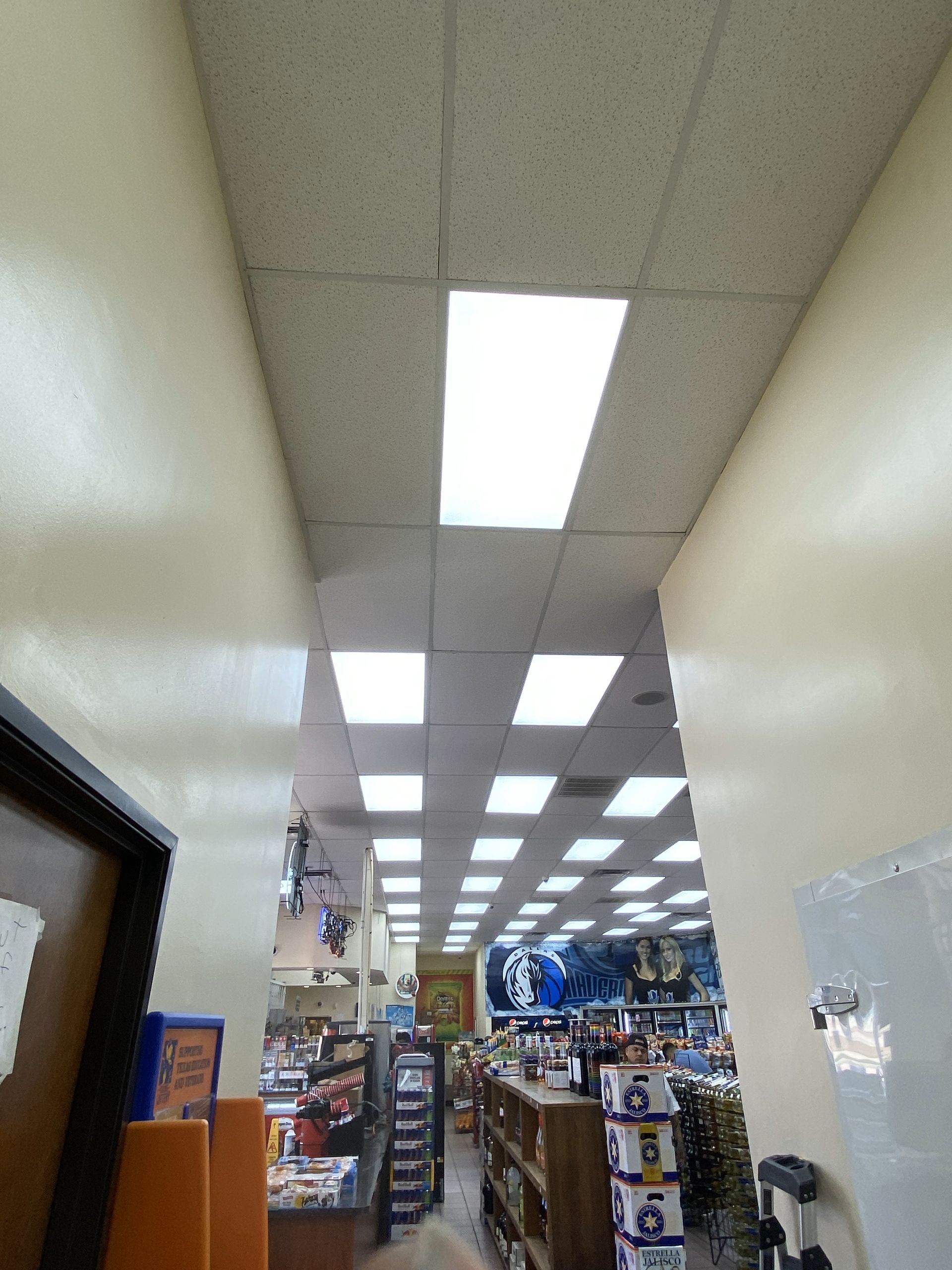Narrow hallway with fluorescent lights, walls and store shelves visible at the end.