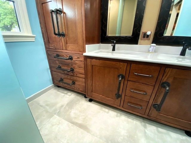 Wooden bathroom vanity with cabinet, drawers, black hardware, white countertop, blue walls, and mirror.