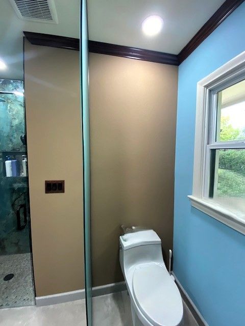 Bathroom interior with a toilet, shower, and blue and tan walls.