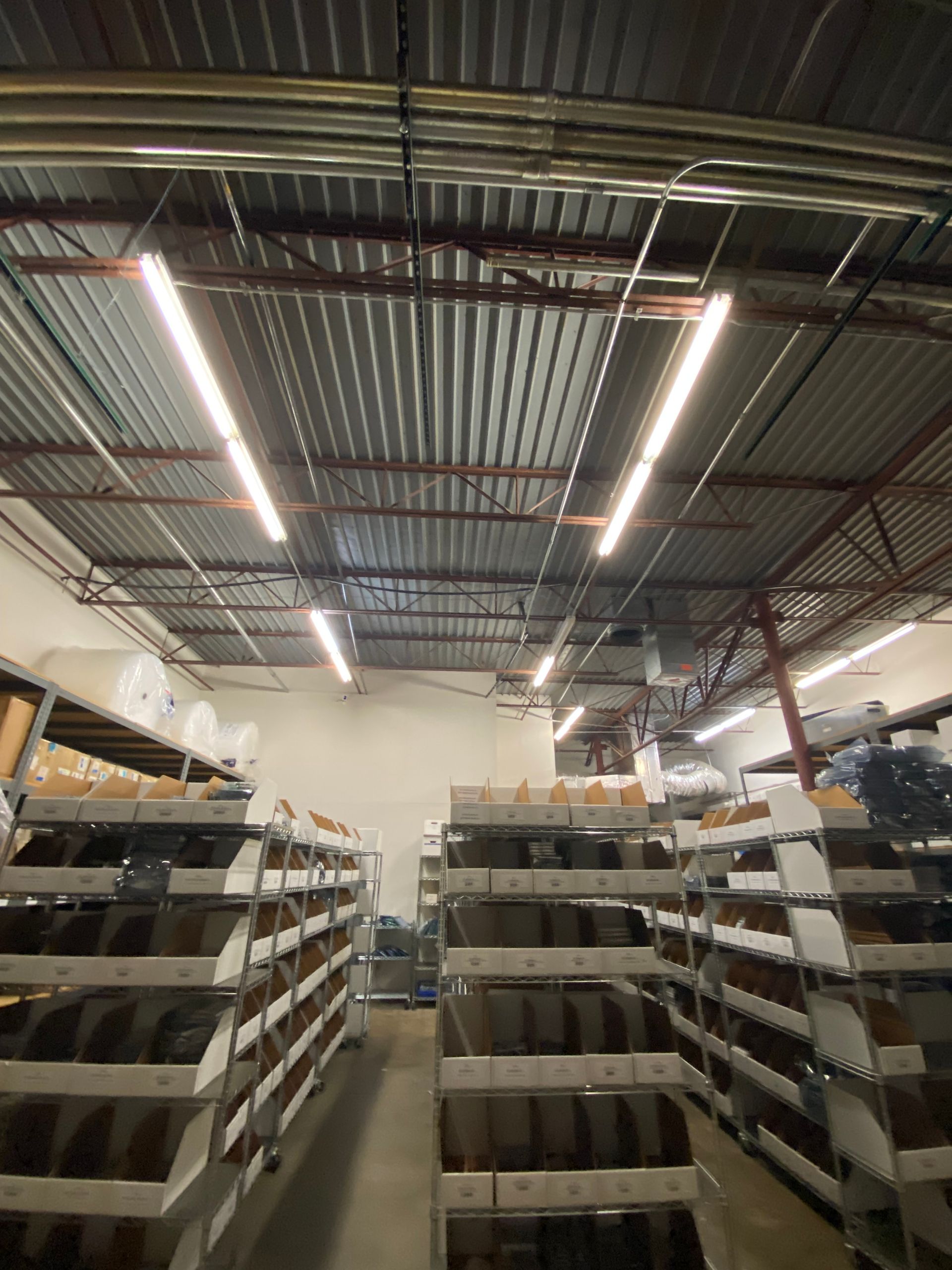 Warehouse interior with shelves, fluorescent lights, and corrugated metal ceiling.