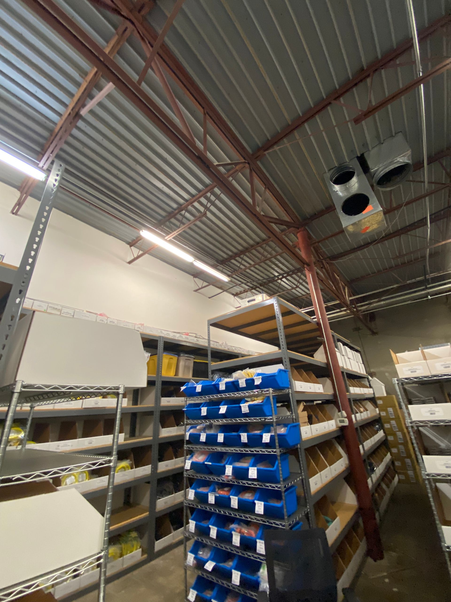 Warehouse interior with metal shelving and blue bins, angled perspective.