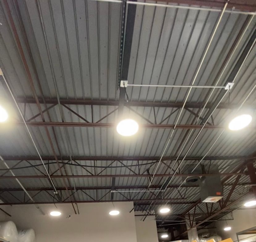 Warehouse ceiling with metal roof, steel beams, and round lights.