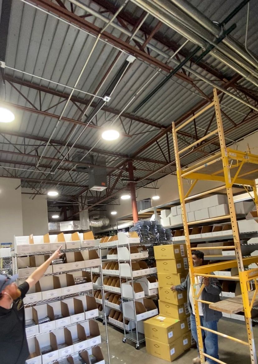 Man pointing up in warehouse with shelving units and exposed ceiling.