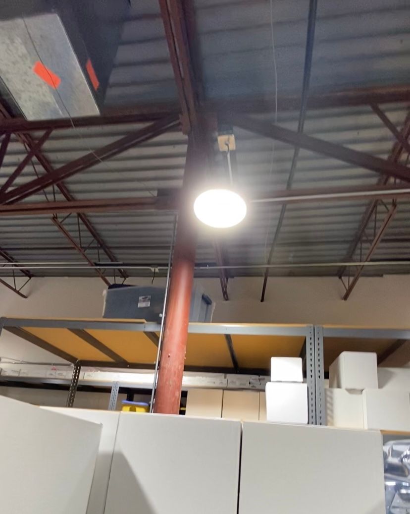 Bright warehouse interior with overhead lighting, metal beams, and storage shelves.