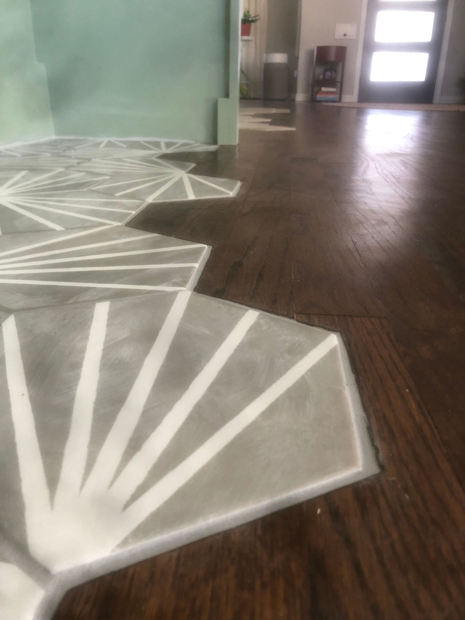 Geometric tile floor in gray and white transitions to dark wood flooring.