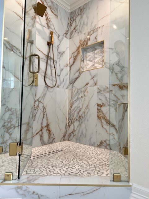 Marble shower with gold fixtures and mosaic floor.