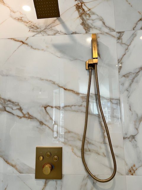 Gold shower fixtures on marble tiled wall.