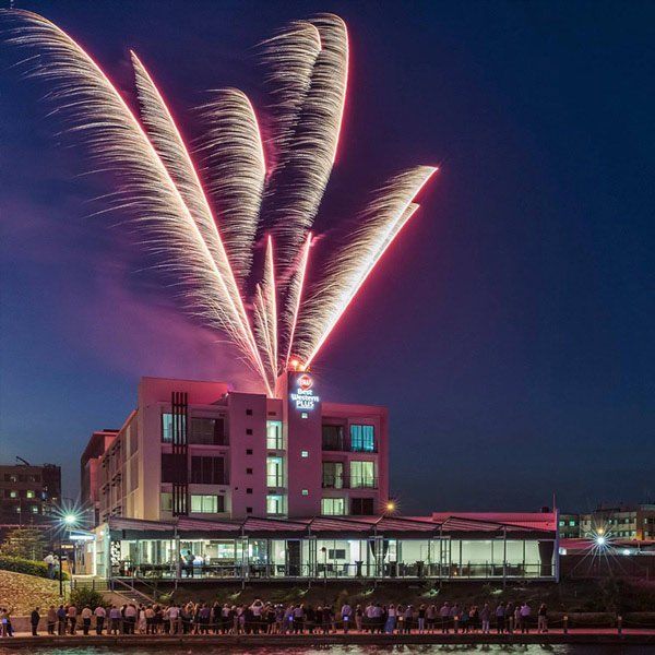fireworks display on roof of modern building with spectators below
