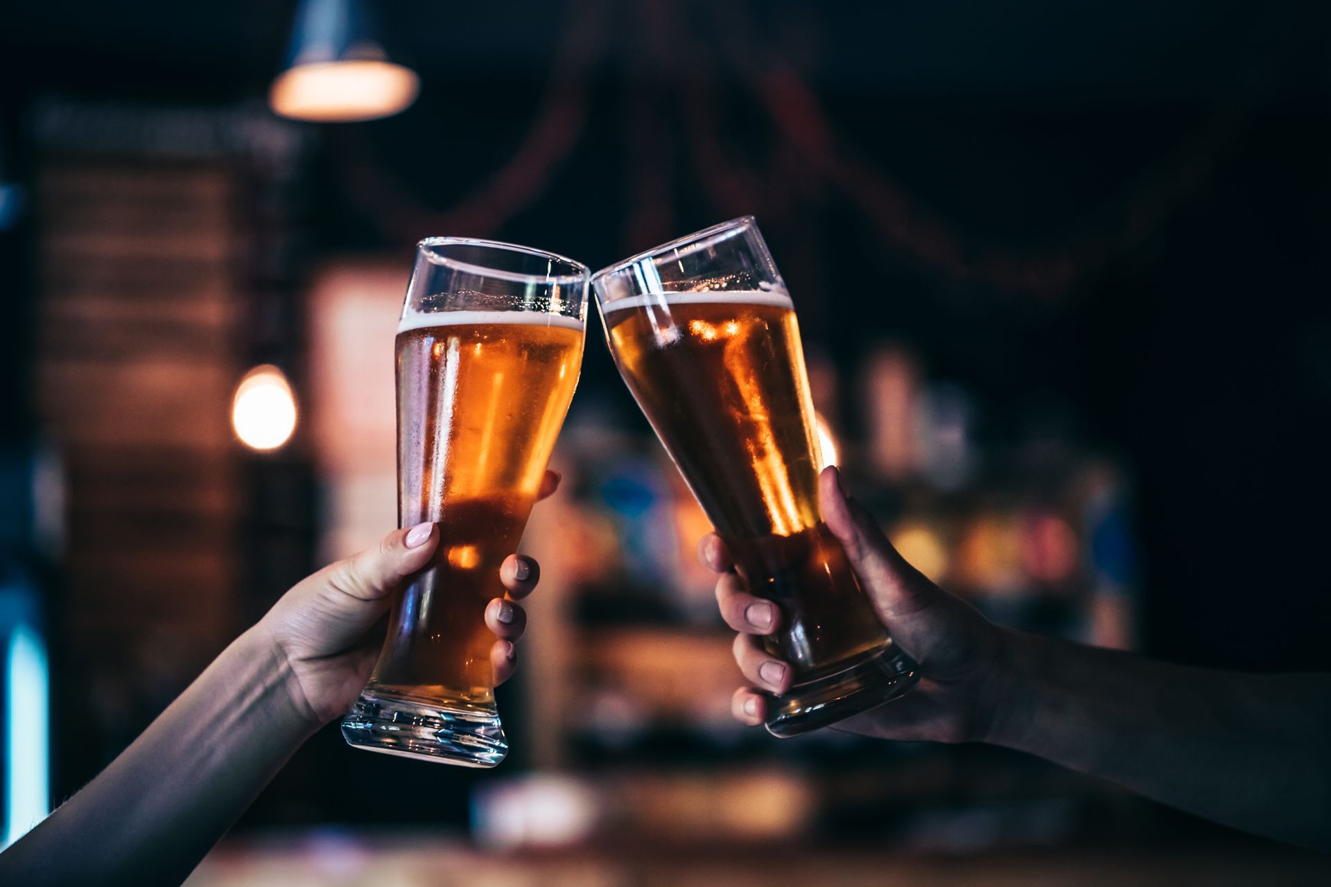 Two friends toasting with glasses of light beer at the pub. Beautiful background of the Oktoberfest. fine grain. Soft focus. Shallow DOF.