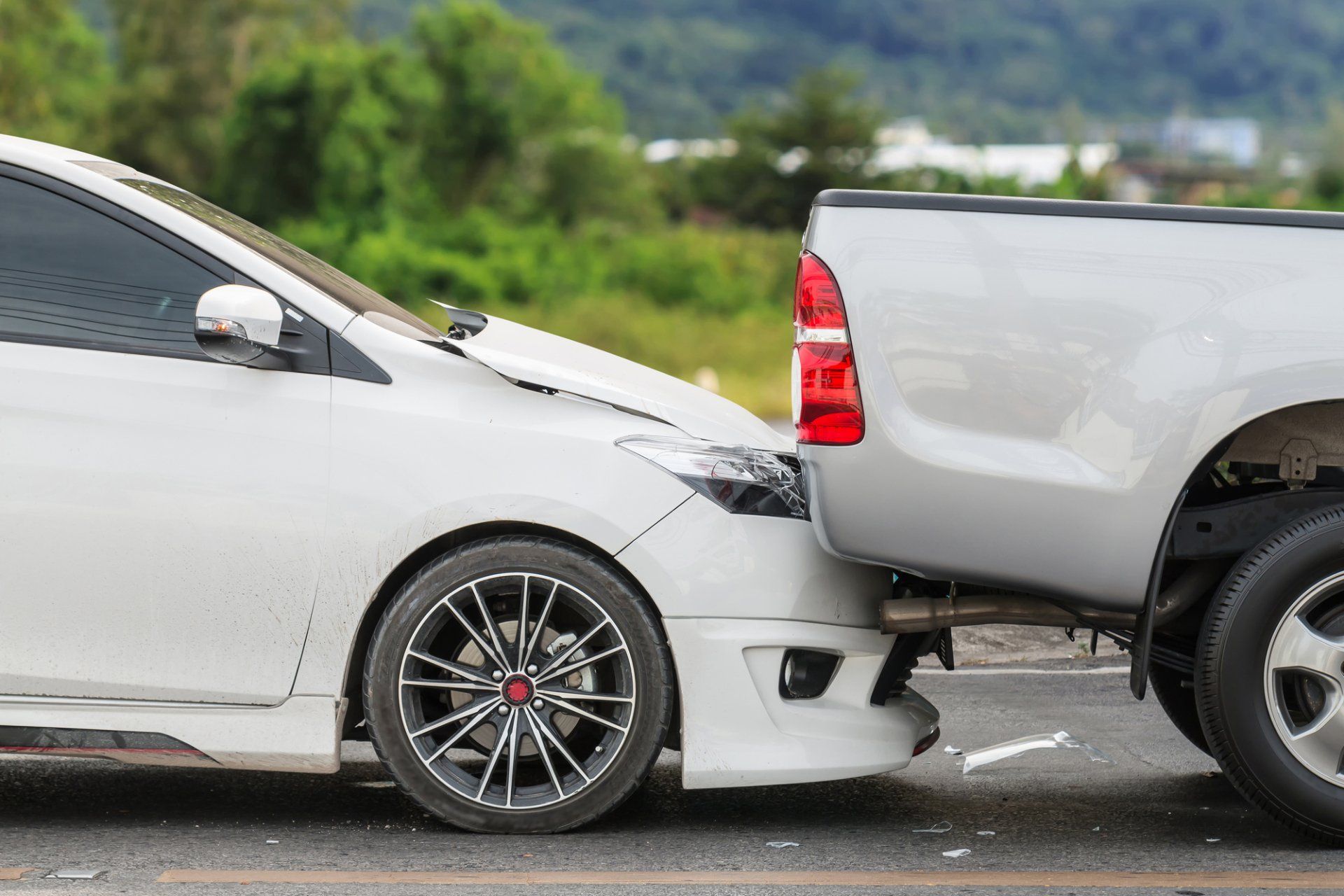 A white car is being towed by a silver truck
