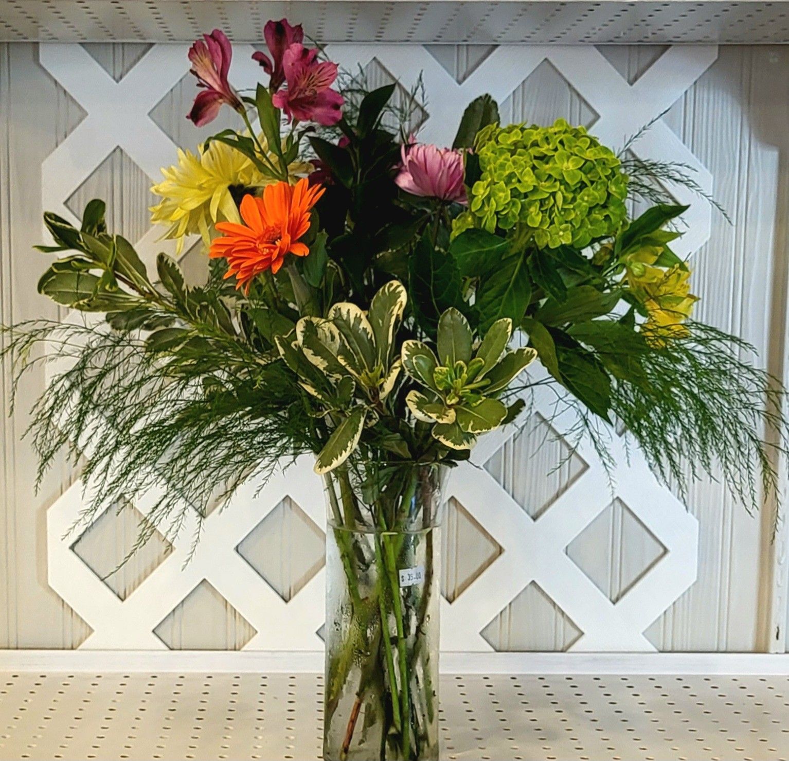A picnic basket filled with food and flowers is sitting on a blanket on the ground.