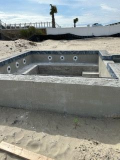 A concrete pool is being built on the beach.