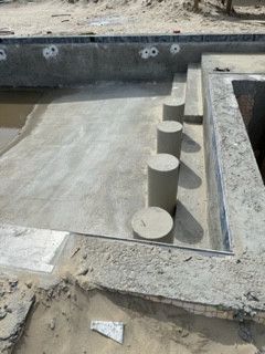 A concrete staircase is being built next to a pool.