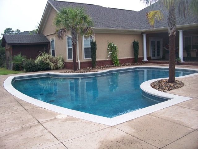 A large swimming pool in front of a house with palm trees