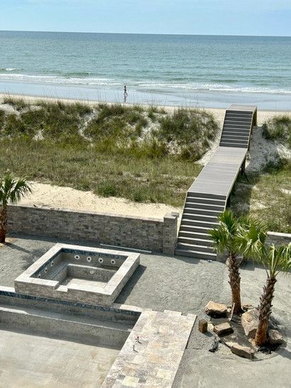 There is a hot tub and stairs leading to the beach.