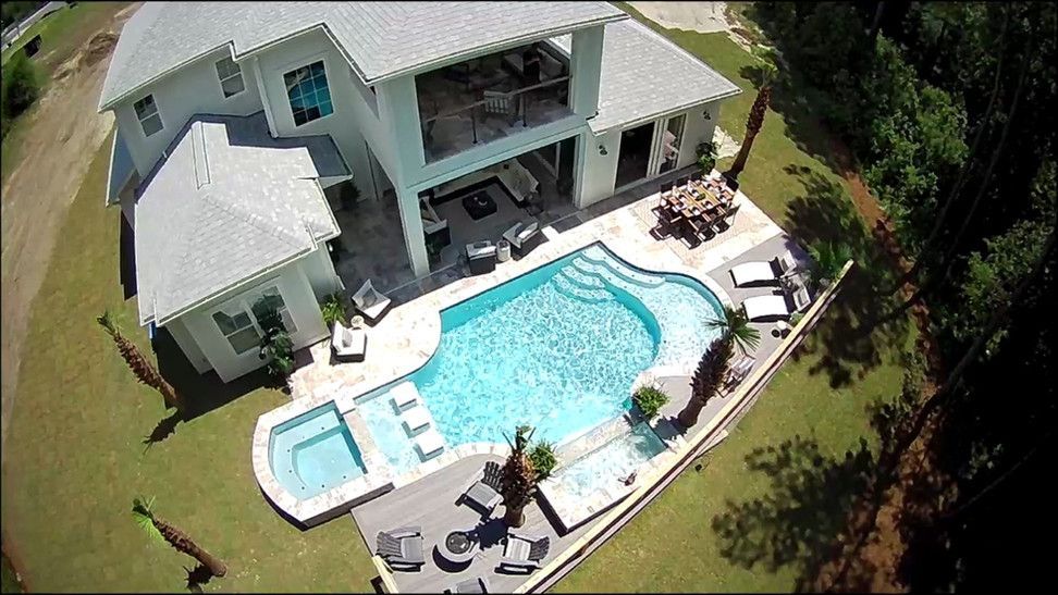 An aerial view of a house with a large swimming pool