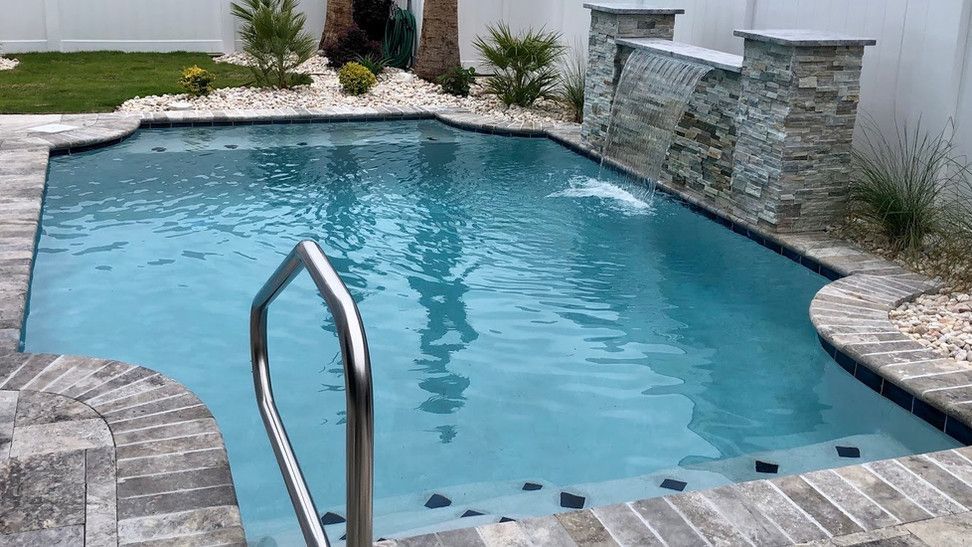 A large swimming pool with a staircase leading to it in a backyard.