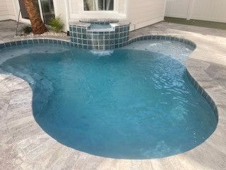 A small swimming pool with a waterfall in the middle of it.