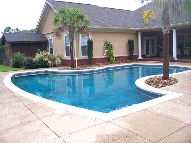 A large swimming pool in front of a house with palm trees